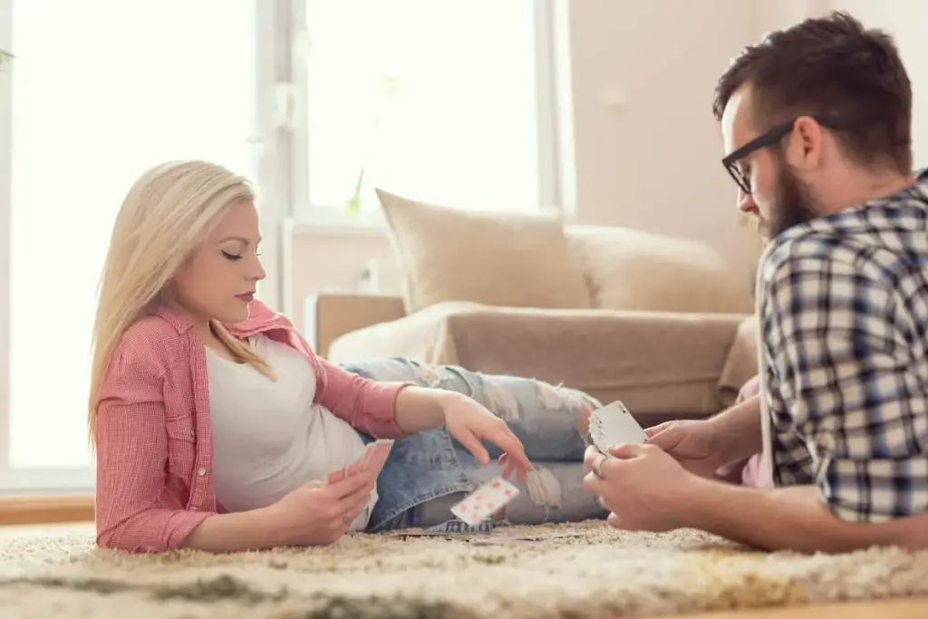 Couple lying on a fluffy rug in a bright living room, playing cards